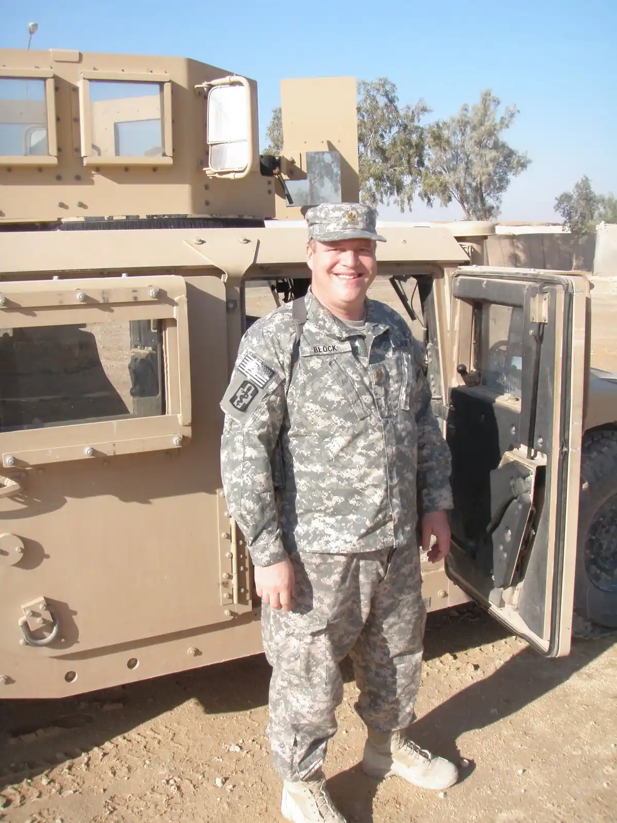 A US Army soldier in combat uniform standing beside an armored Humvee at Al Asad, Iraq.