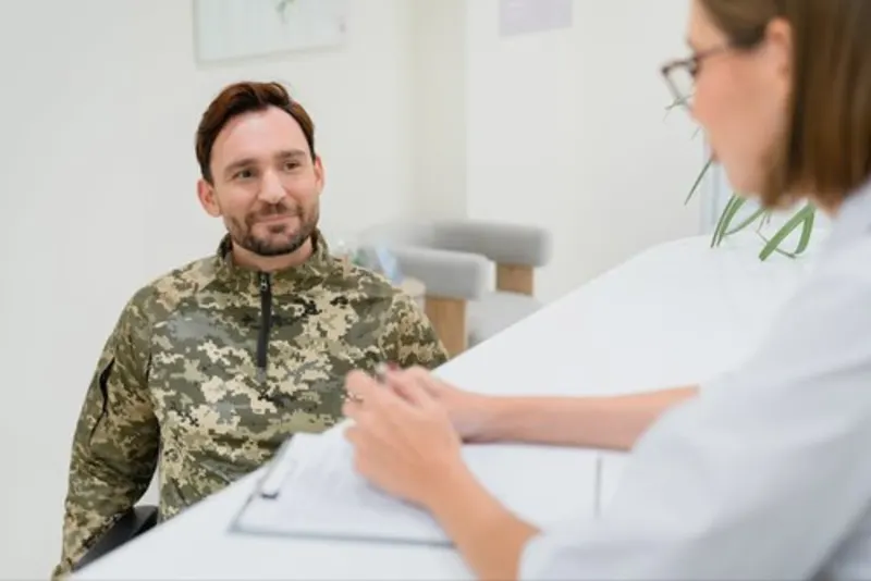 Smiling service member in uniform talking with a clinician across a desk