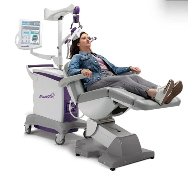 Woman reclining in a NeuroStar TMS chair with the treatment coil positioned against her head