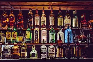 Backlit shelves of whiskey, gin and other liquor bottles behind a bar