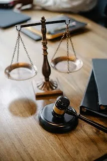 Brass balance scales and a wooden gavel on a desk beside stacked law books