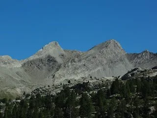 Bare rocky peaks of the Trois-Évêchés massif in the French Alps above a pine forest