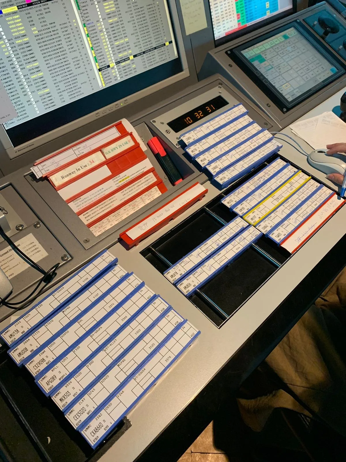 Air traffic control console with racks of handwritten paper flight progress strips